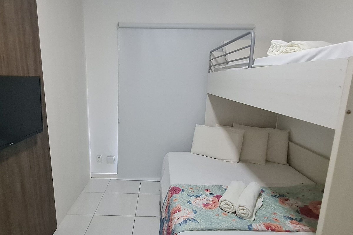 A bunk bed with a TV mounted on the wall, a door, and a tiled floor.