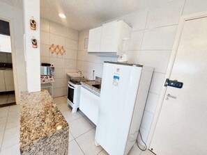 A compact kitchen with white appliances, a granite countertop, and a tiled backsplash.