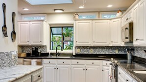 A modern kitchen with white cabinets, a black countertop, and a skylight. - Lakefront Hot Springs Vacation Rental w/ Dock! (Hot Springs)
