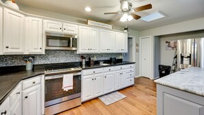 A modern kitchen with white cabinets, stainless steel appliances, and a ceiling fan. - Lakefront Hot Springs Vacation Rental w/ Dock! (Hot Springs)