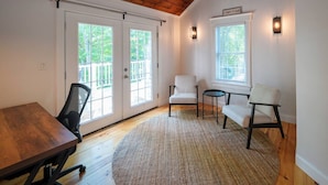 A room with a wooden ceiling, a large table, two chairs, a small round table, and a rug. - Yarmouth Port Escape Minutes to the Beach (Yarmouth)