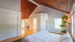 A bedroom with a large bed, wooden ceiling, white walls, and a view of the outdoors. - Yarmouth Port Escape Minutes to the Beach (Yarmouth)