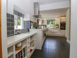 Una cocina moderna con armarios blancos, horno empotrado y ventana que proporciona luz natural.