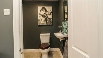 A bathroom with a toilet, sink, and a wall-mounted mirror.