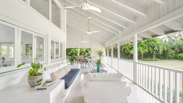 A spacious, well-lit room with a high ceiling, large windows, and a view of a lush garden. - Closest villa in Casa to Minitas Beach with private pool, garden, screened patio (La Romana)