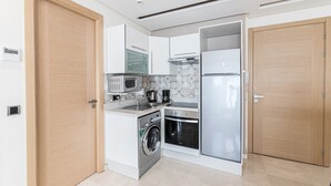Een kleine keuken met een wasmachine, magnetron en koelkast.