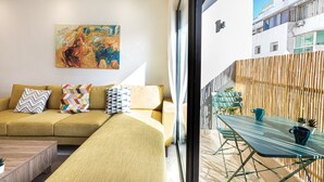 Een moderne woonkamer met een bank, kleurrijke kussens en een schilderij aan de muur.