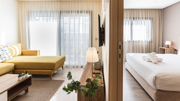 Een hotelkamer met een bed, een sofa, een bureau met lamp en een televisie aan de muur.