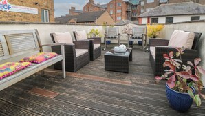A rooftop patio with wicker furniture, a bench, and potted plants. - 50 West Street Edelweiss (Scarborough)