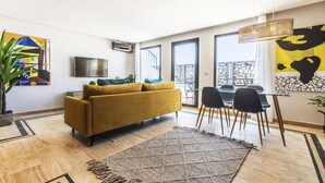 Ein modernes Wohnzimmer mit einer Couch, einem Esstisch, Stühlen und einem Fernseher.