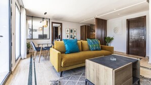 Ein modernes Wohnzimmer mit einem gelben Sofa, einem Couchtisch und einem Essbereich mit Stühlen und einem Tisch.
