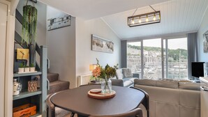 A modern living room with a dining table, sofas, and a city view through large windows.