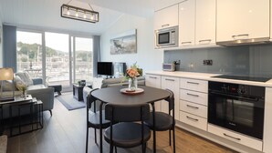 A modern kitchen with white cabinets, a Bosch oven, and a dining area with a round table and chairs.