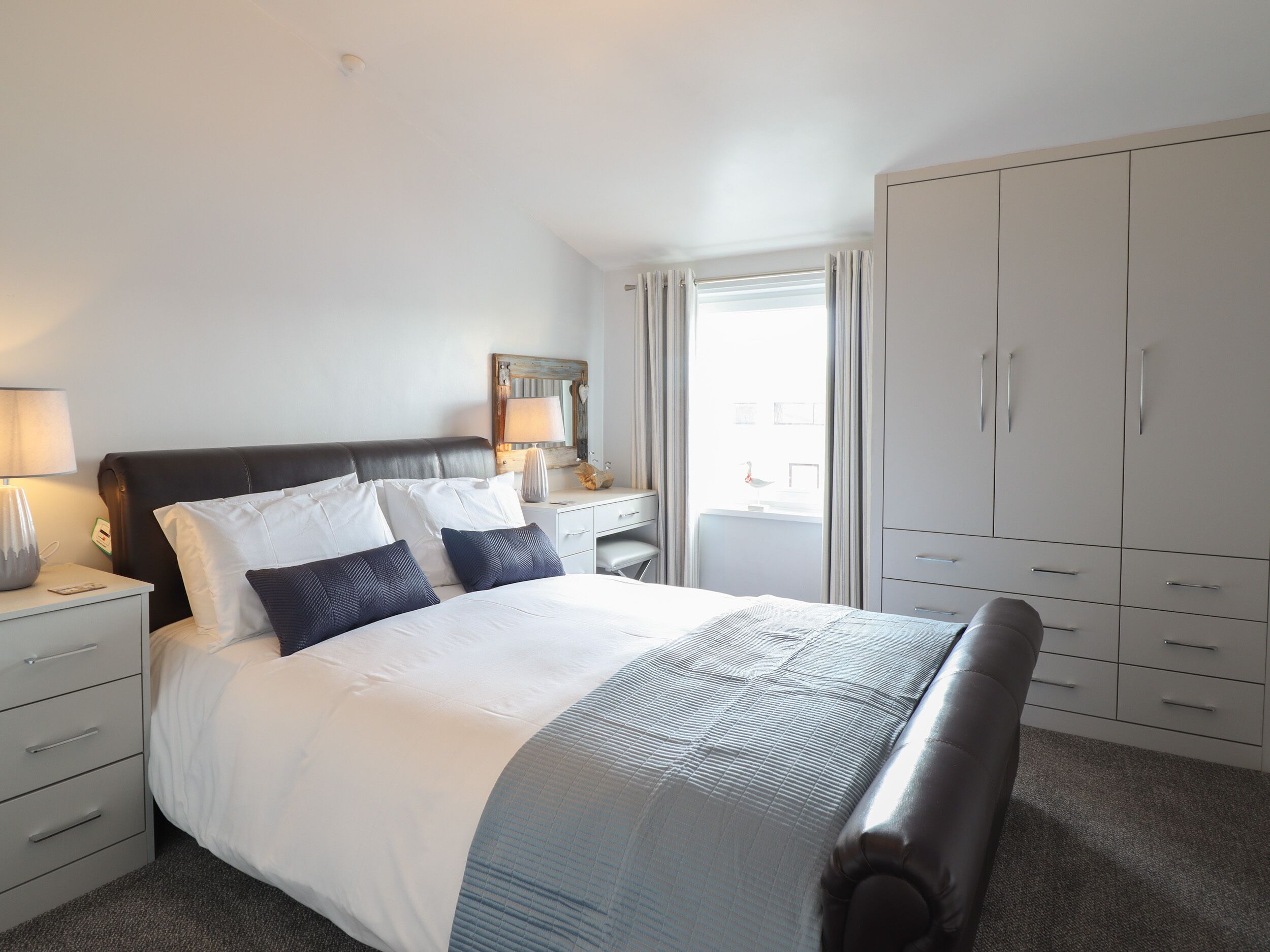 A hotel room with a bed, a nightstand, a dresser, and a wardrobe.