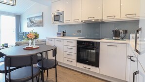A modern kitchen with white cabinetry, a Bosch oven, a microwave, and a kettle.