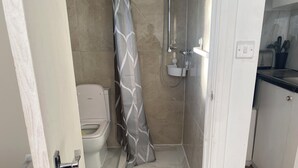 Une petite salle de bain comprenant une douche, des toilettes et un lavabo.