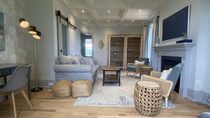A spacious living room with a sofa, armchairs, a coffee table, and a fireplace. - Thunderbird Farm - Luxury 5-Bedroom Farmhouse w/ Pool & Hands-On Farm Experience (Kawartha Lakes)