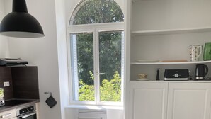 Een moderne keuken met een eettafel, stoelen en een groot raam.