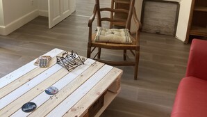 Een kamer met een houten salontafel, een rode stoel, een houten bureau en een open haard.