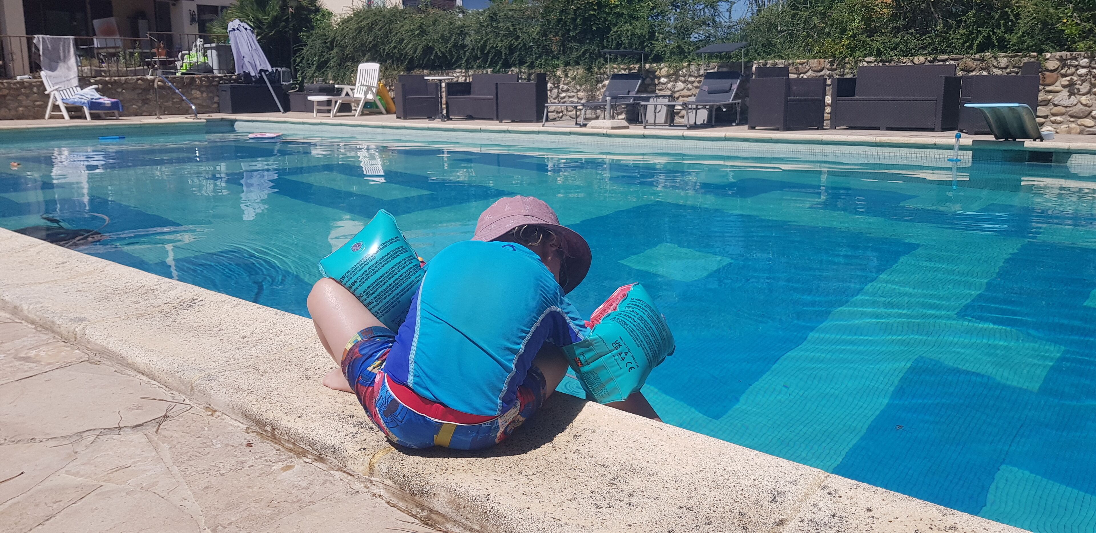 Una piscina con lettini e un muro in pietra sullo sfondo.