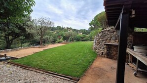 A well-maintained lawn with a stone wall and a metal structure. - Sous le grand pin: swimming pool and spa (Gîtes Eden en Cévennes) in Anduze (Anduze)
