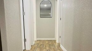 Un couloir avec un plancher en bois et des murs blancs.