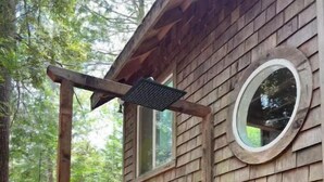 A wooden cabin with a wooden deck and a circular window.
