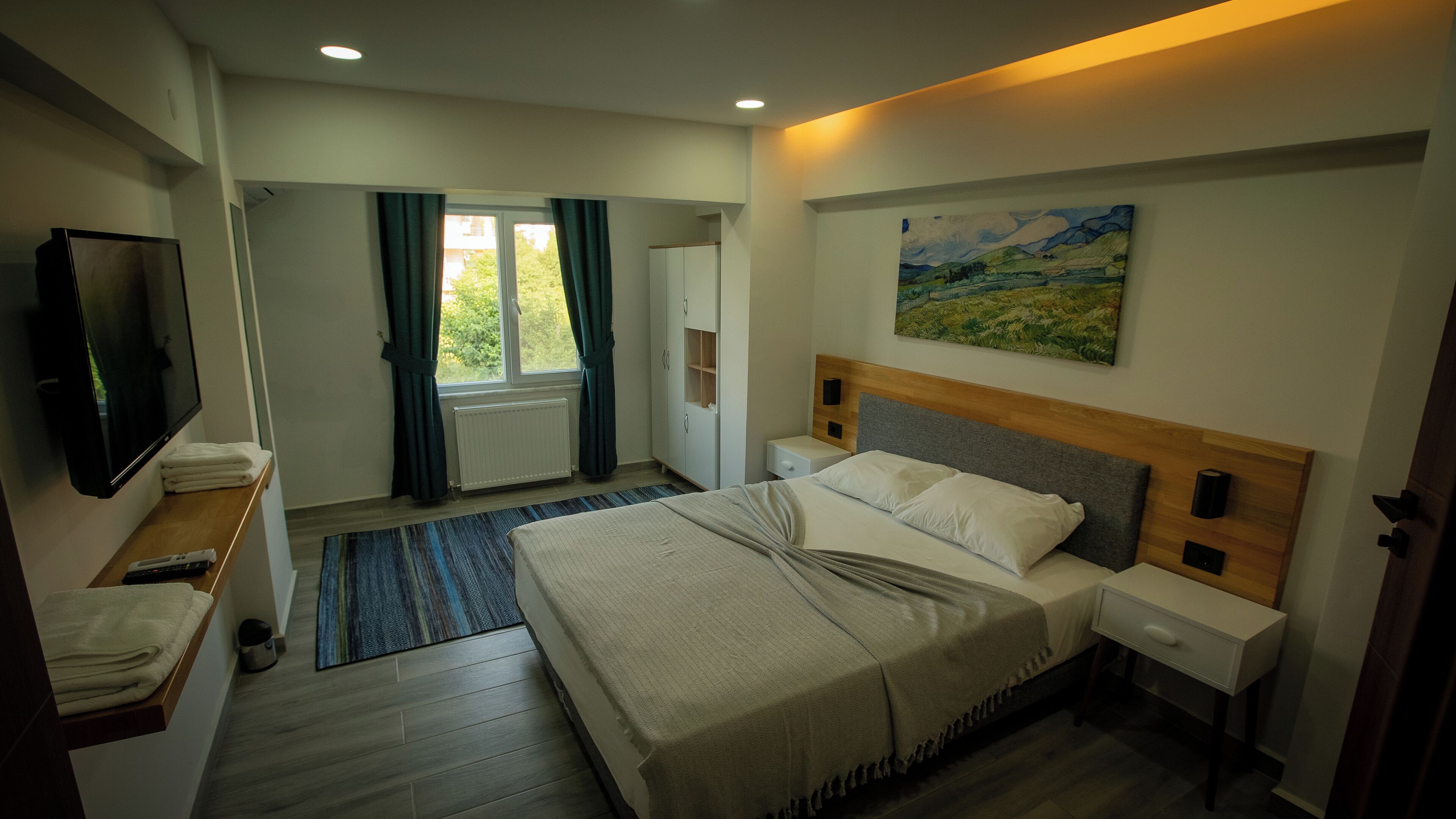 Une chambre d’hôtel avec un lit, des tables de chevet, une télévision, un tableau et une vue sur l’extérieur.