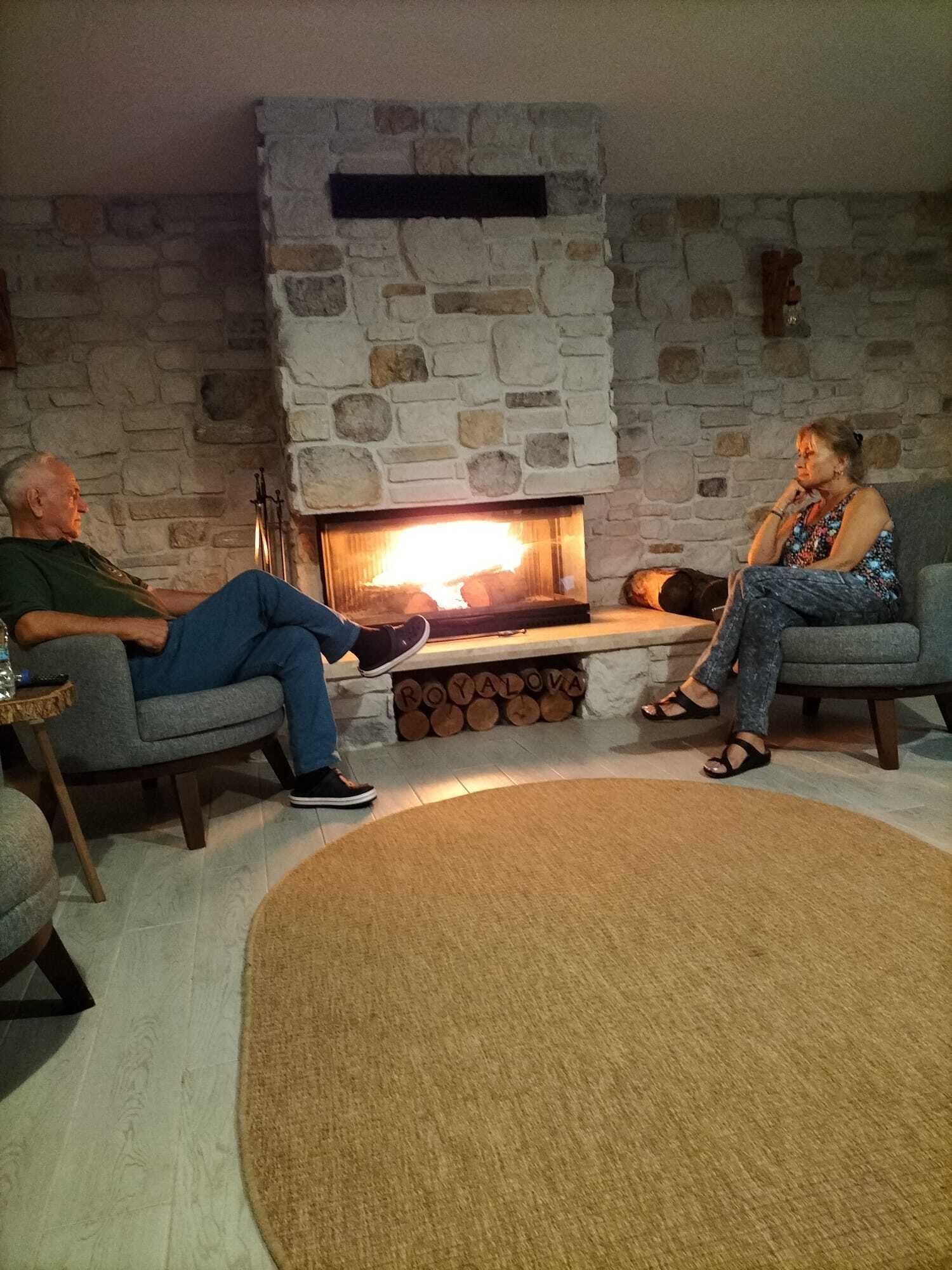 A cozy living room with a stone fireplace, two armchairs, and a round rug.