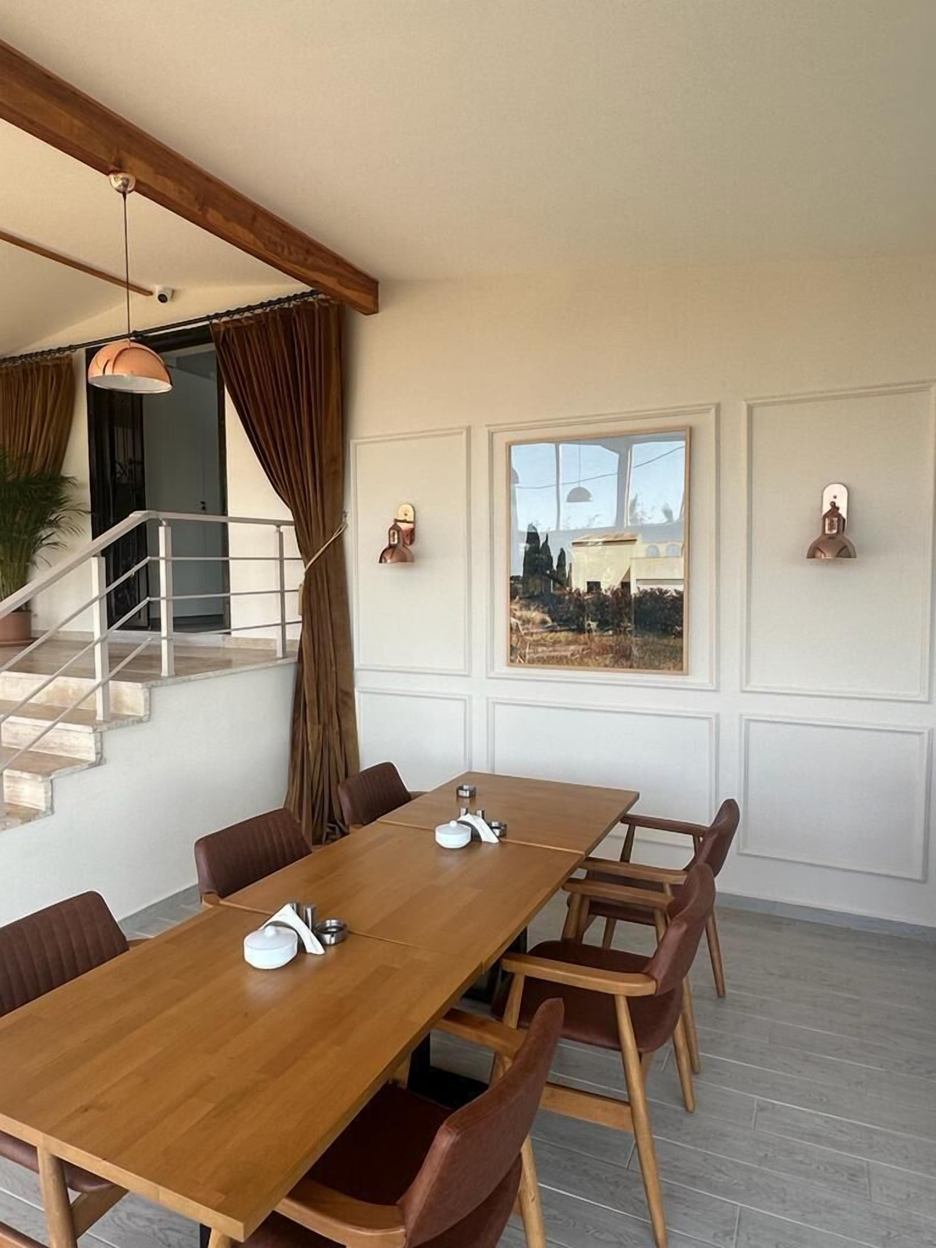 A dining area with a wooden table, brown chairs, and a view of a landscape through a window.