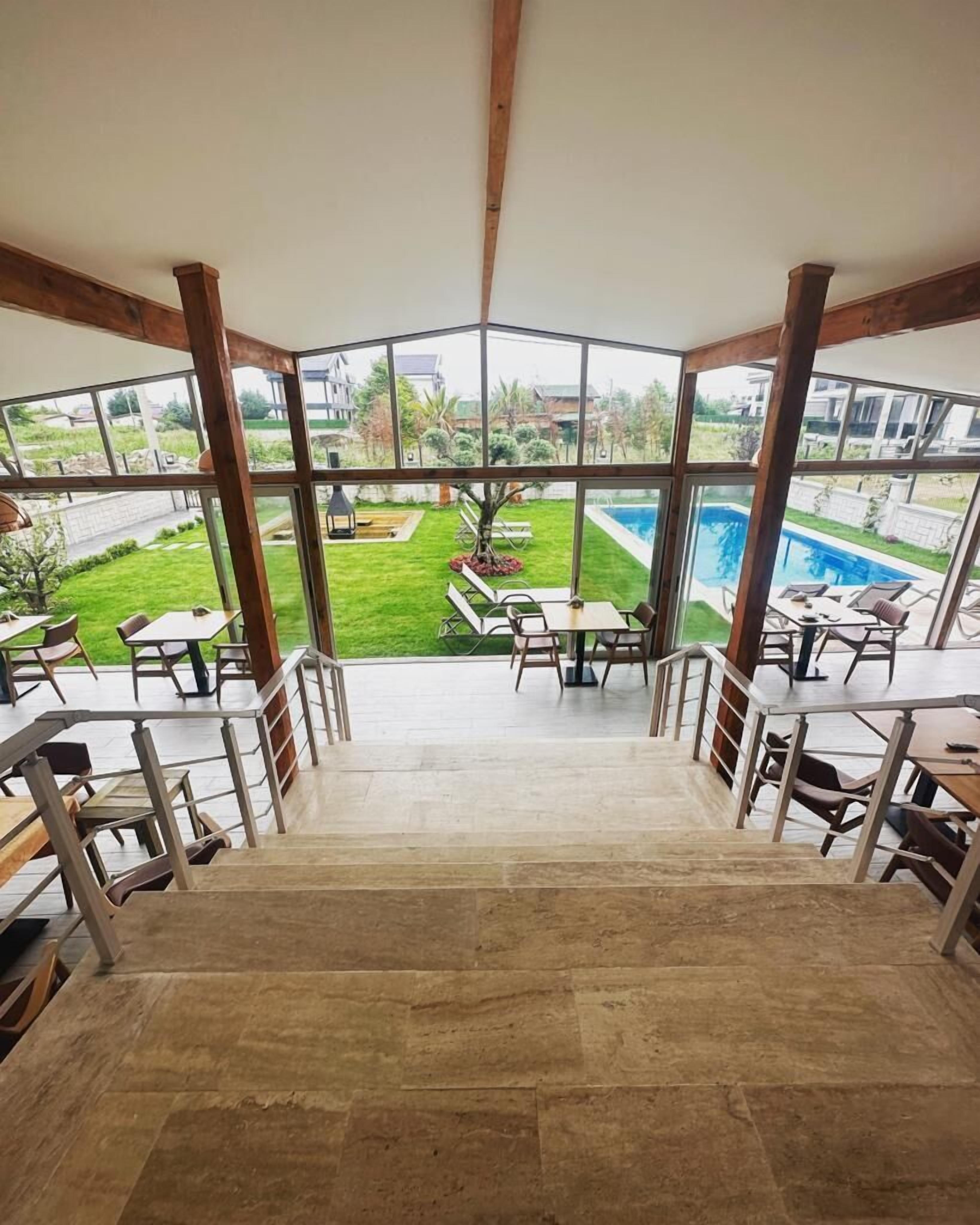 A spacious indoor area with a view of a swimming pool and a well-maintained garden.