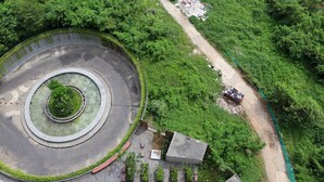 An aerial view of a roundabout with a central green space, surrounded by dense greenery and a dirt path. - Modern Look and Homey Studio Apartment LRT City Jatibening (Bekasi)