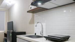 A modern kitchen with a double sink, a built-in stove, and a flat-screen TV. - Modern Look and Homey Studio Apartment LRT City Jatibening (Bekasi)