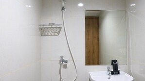 A bathroom with a shower, a sink, and a mirror. - Modern Look and Homey Studio Apartment LRT City Jatibening (Bekasi)