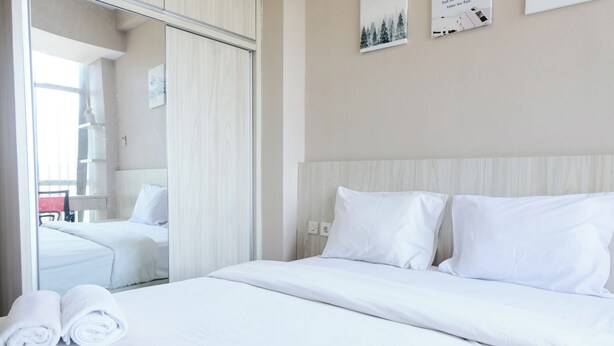 A hotel room with a large bed, a mirror, and a view of another room. - Best Choice 2Br Apartment At Taman Melati Jatinangor (Hegarmanah)