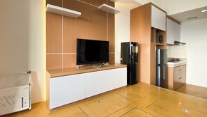 A modern kitchen with a built-in TV, a water dispenser, and a stove. - Nice And Cozy Studio Apartment At Vasanta Innopark (Cikarang)