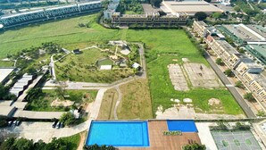 An aerial view of a large complex with multiple buildings, a central courtyard, and a swimming pool. - Nice And Cozy Studio Apartment At Vasanta Innopark (Cikarang)