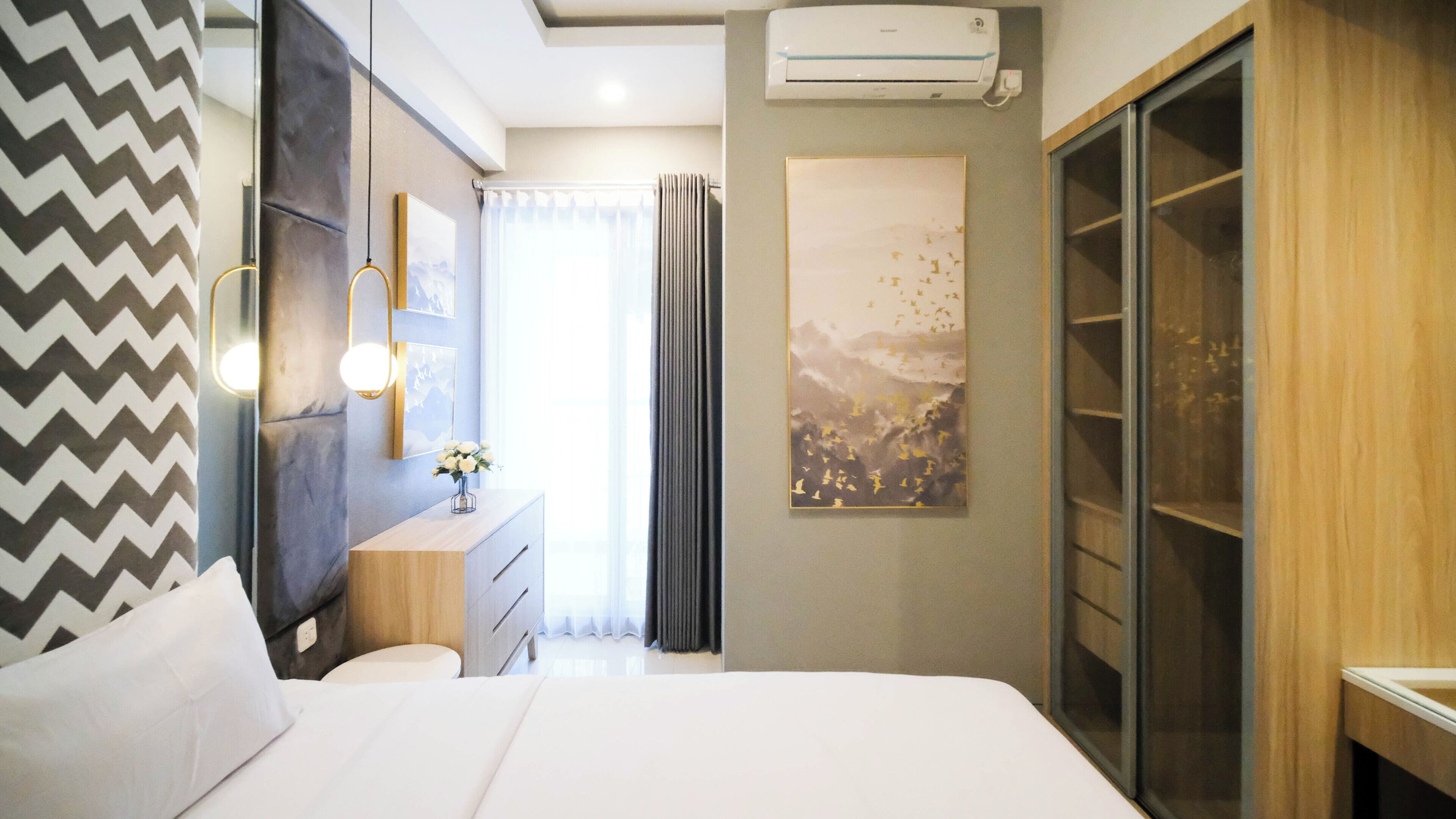 Una habitación de hotel moderna con una cama, una tocador con espejo, una ventana con cortinas y un equipo de aire acondicionado.