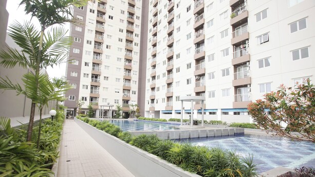 A residential building with multiple balconies, a swimming pool, and surrounding greenery.