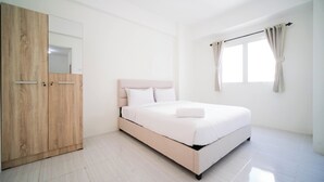 A minimalist bedroom with a bed, wooden wardrobe, and a window with curtains.