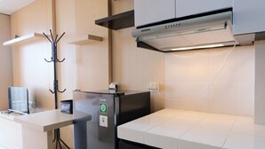 Ett modernt kök med ett svart kylskåp, vita bänkskivor och en inbyggd köksfläkt.