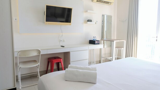 Een hotelkamer met een bed, een bureau, een stoel, een televisie, een spiegel en een raam met gordijnen.