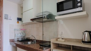 Een keuken met een granieten aanrecht, een roestvrijstalen spoelbak, een zwarte magnetron en een koffiezetapparaat.