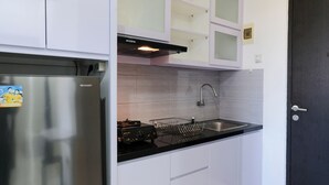 Una cucina moderna con mobili bianchi, un frigorifero in acciaio inossidabile, un piano di lavoro nero e un piano cottura integrato.