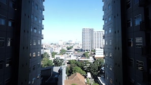 Un edificio alto con diversi piani e balconi, circondato da altri edifici e alberi.