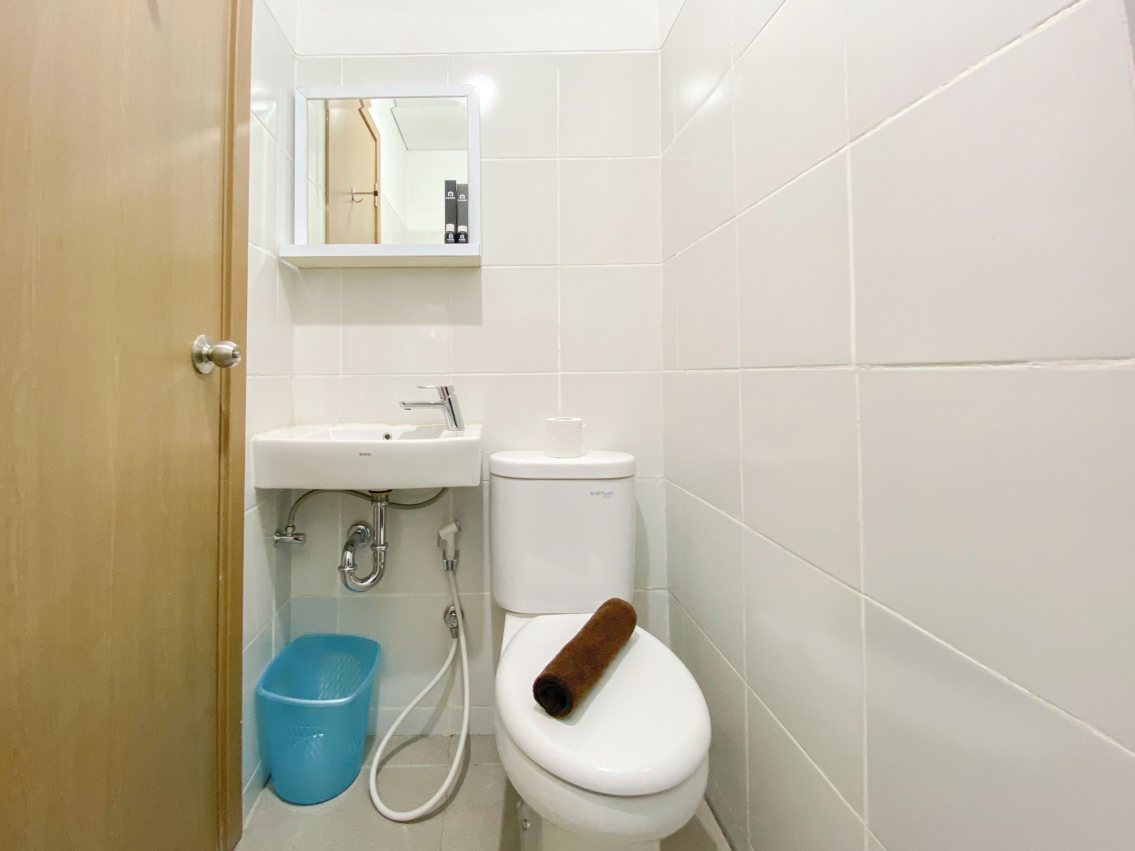A bathroom with a toilet, sink, and blue trash bin.