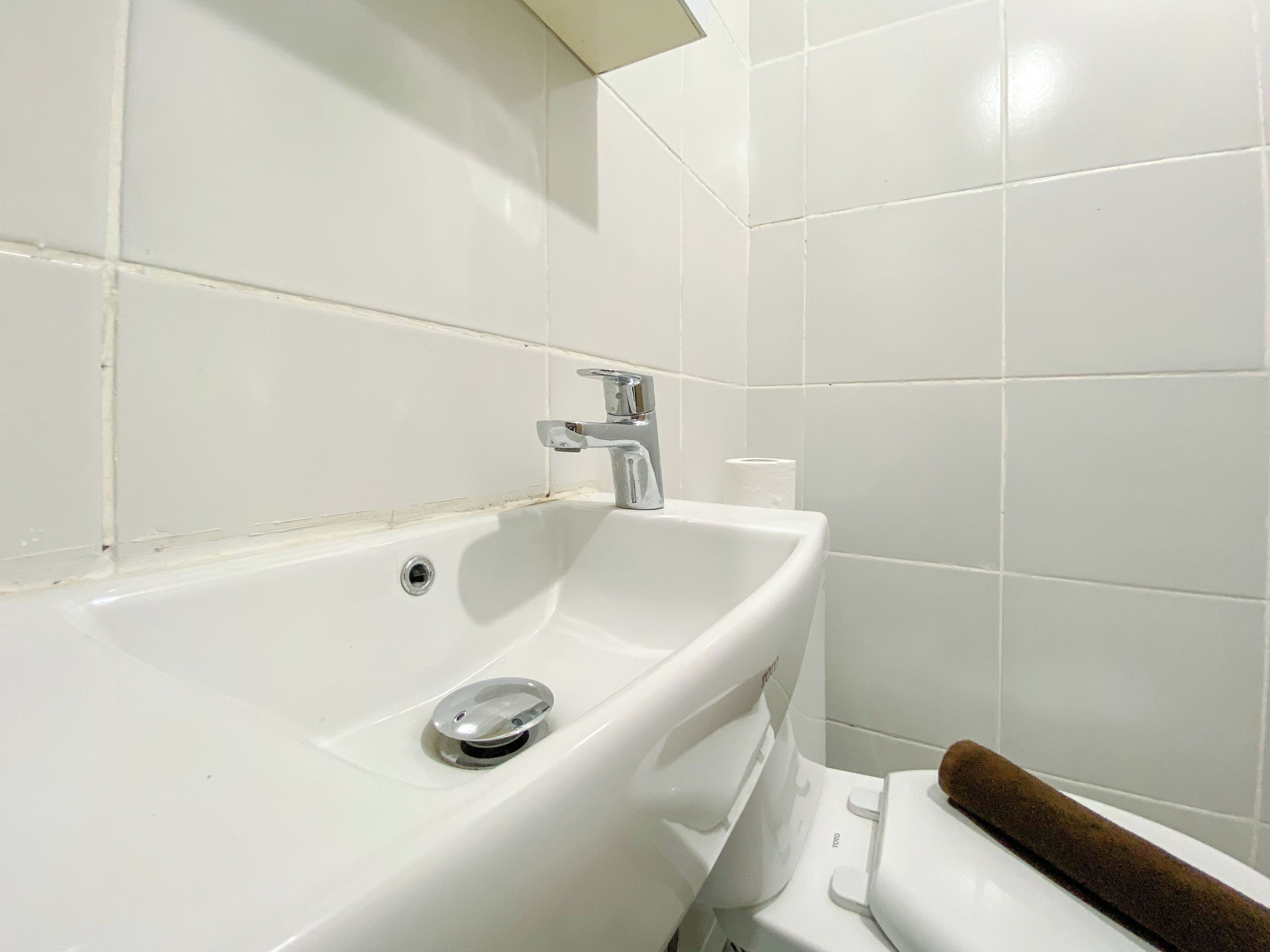A white bathroom with a sink, faucet, and toilet.