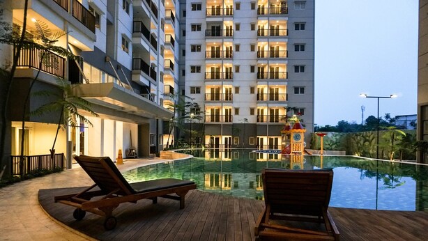 A hotel pool area with lounge chairs and a water feature. - Minimalist Studio Apartment Signature Park Grande (Jakarta)