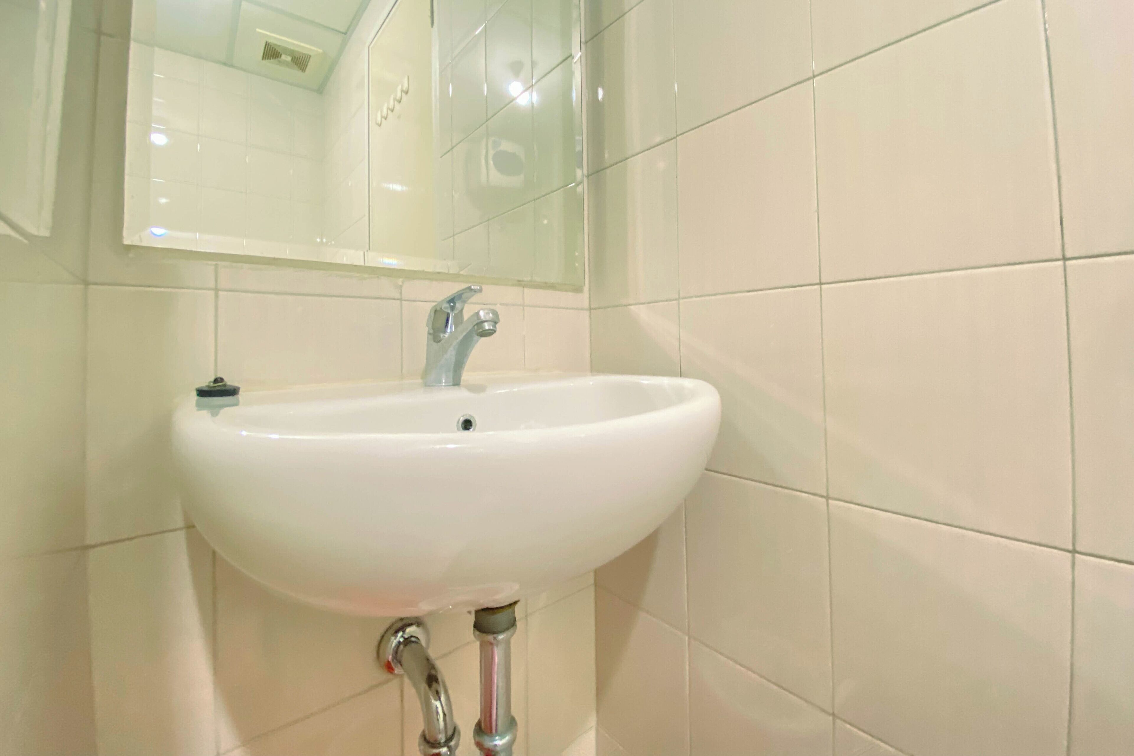 A bathroom with a white sink, a mirror, and tiled walls.