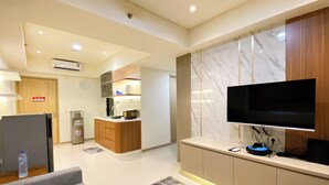 A modern kitchen with a built-in microwave, a coffee machine, and a TV mounted on the wall. - Comfortable Designed And Best Deal 2Br At Meikarta Apartment (Cikarang)